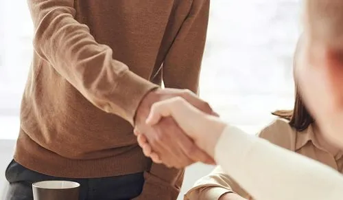 a man in a brown sweater shaking hands