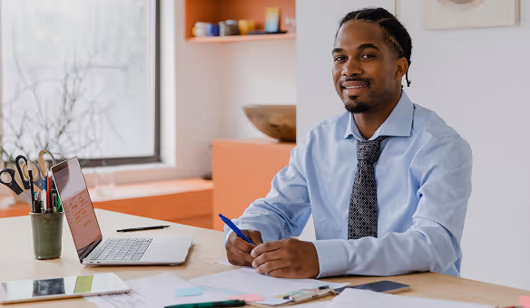 a man in a blue shirt and tie sitting at a table.