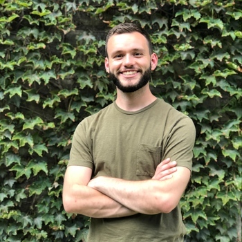 Sam Hodge smiling in front of an ivy-covered wall