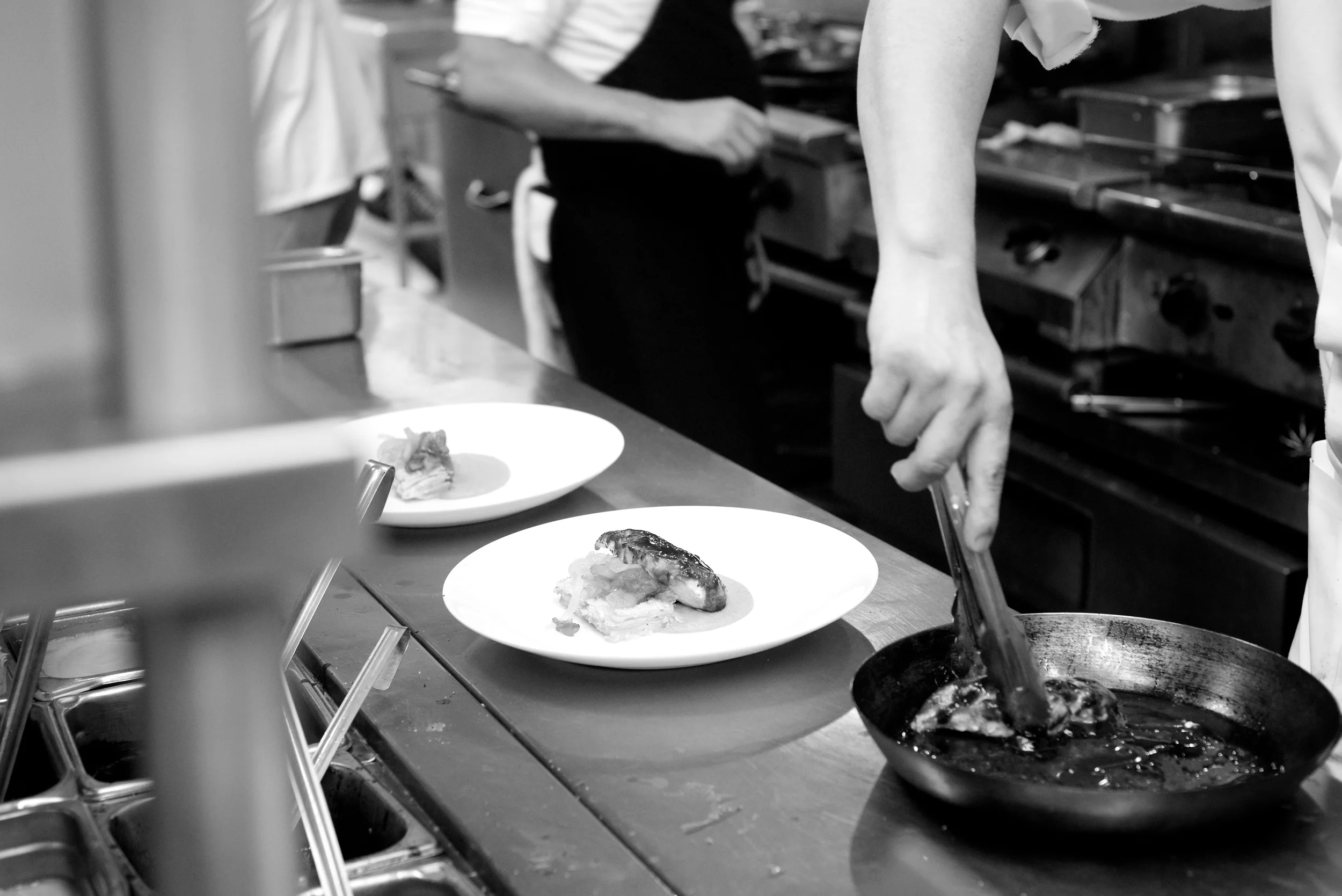 A chef plating dishes on the pass in the La Palapa kitchen