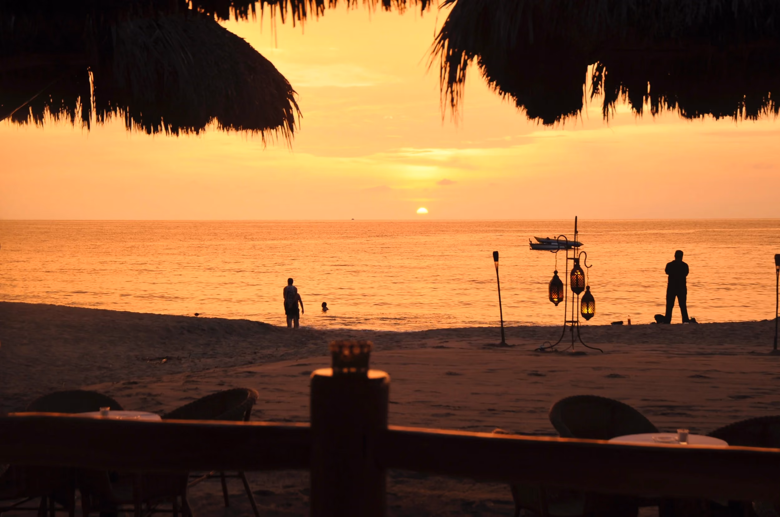 Sunset over Los Muertos Beach framed by La Palapa’s thatched roof