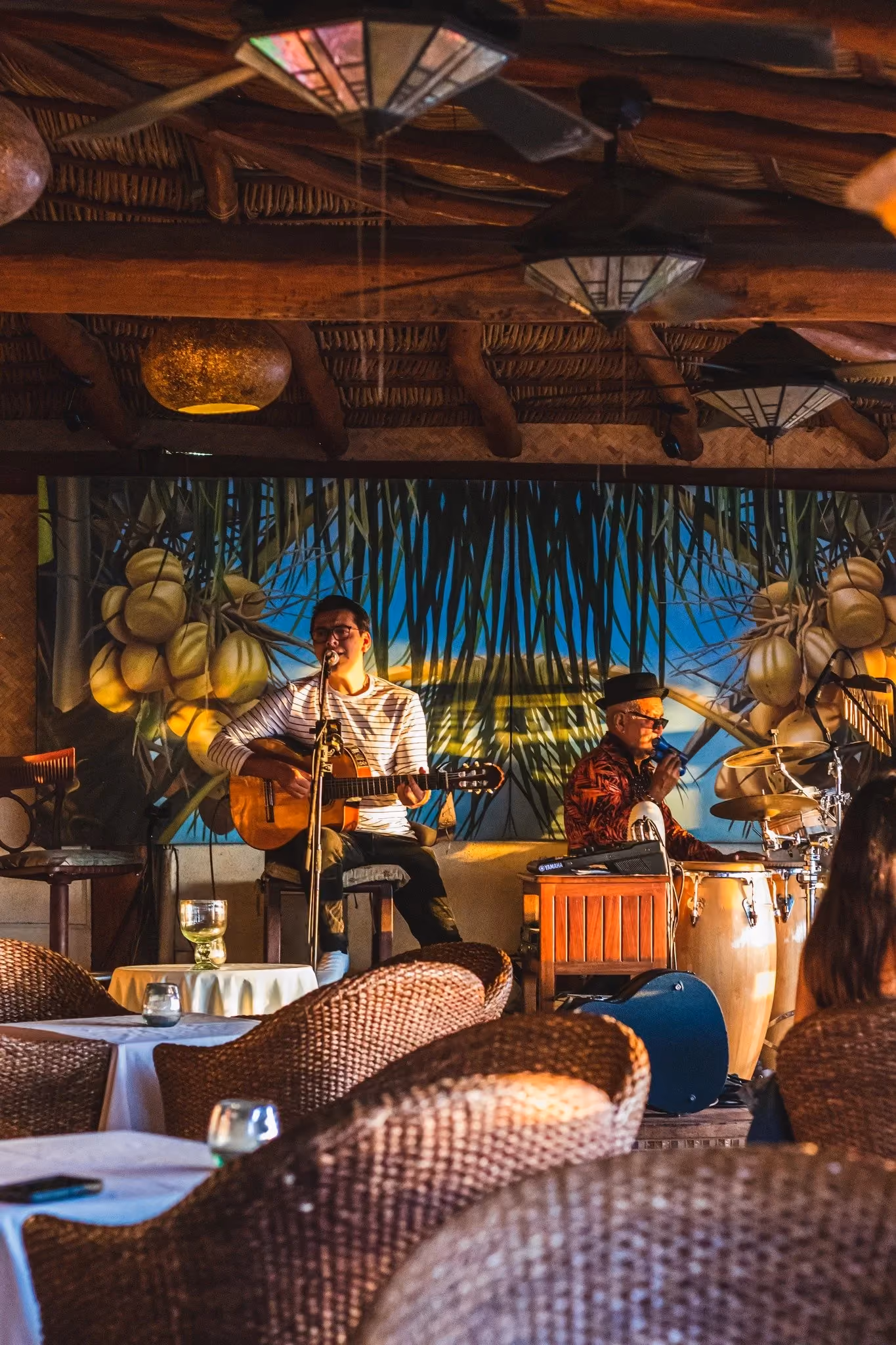 Guitarist and percussionist playing live under the palapa roof at La Palapa