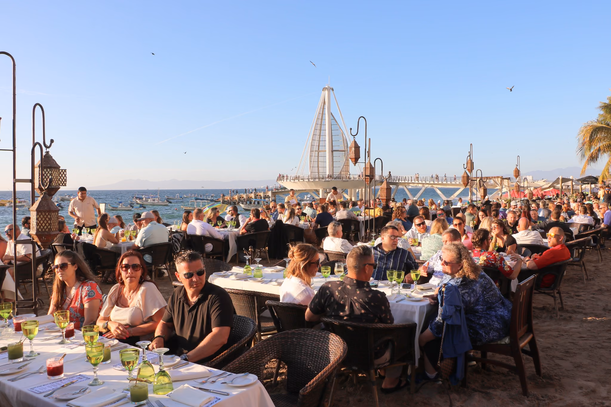 A full terrace of guests dining on the sand by the Los Muertos Pier