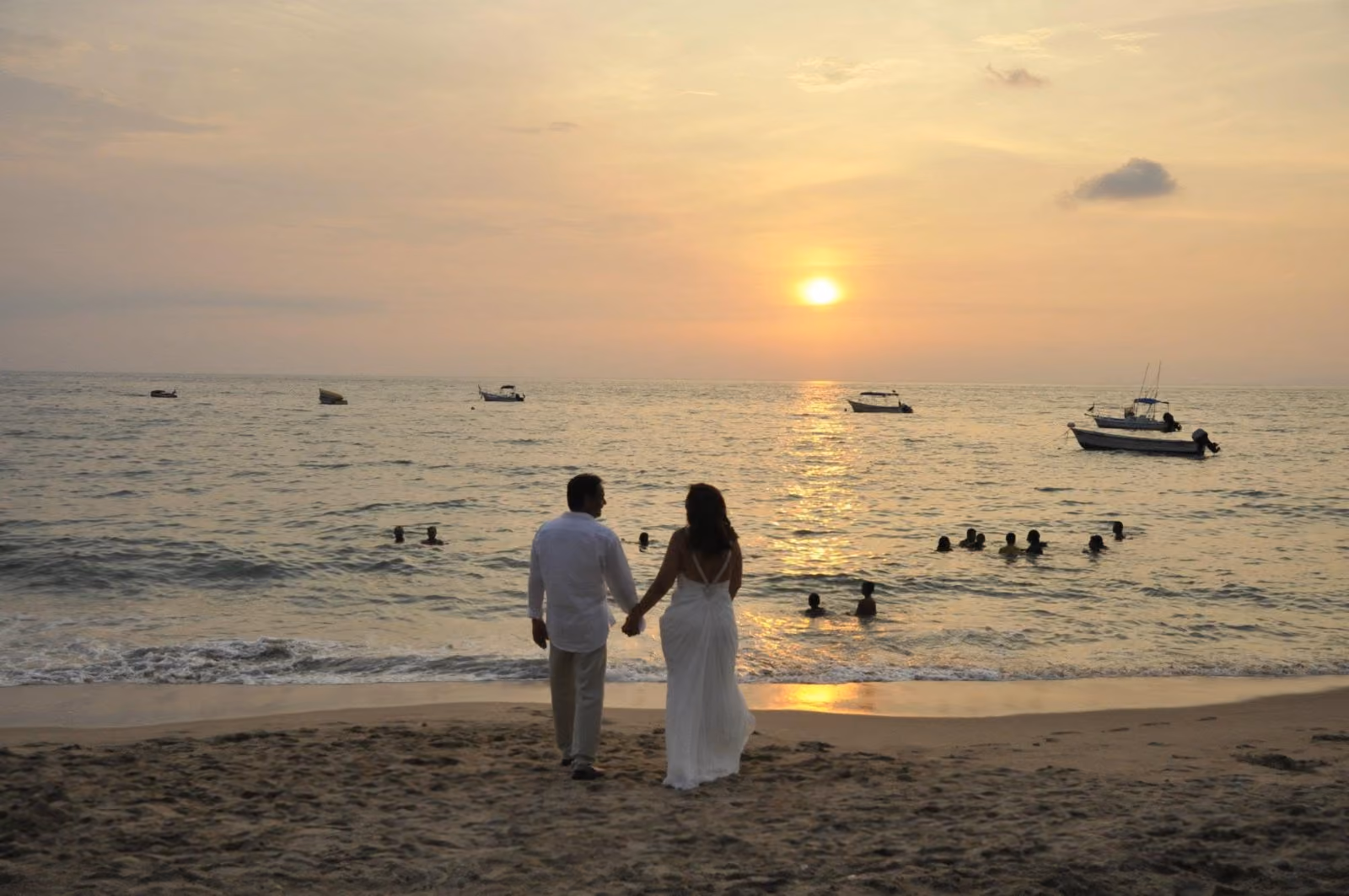 A bride and groom on the beach in front of La Palapa at sunset