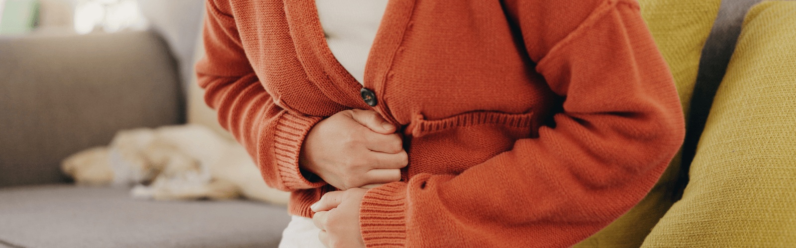 Person holding their stomach with abdominal pain at home, a symptom of Crohn's disease—seeks care from the best gastroenterologist in Los Angeles.