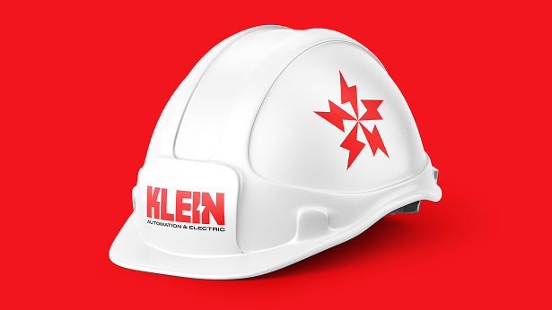 White construction hardhat with red geometric logo and text 'KLEIN Automation & Electric' on a red background.