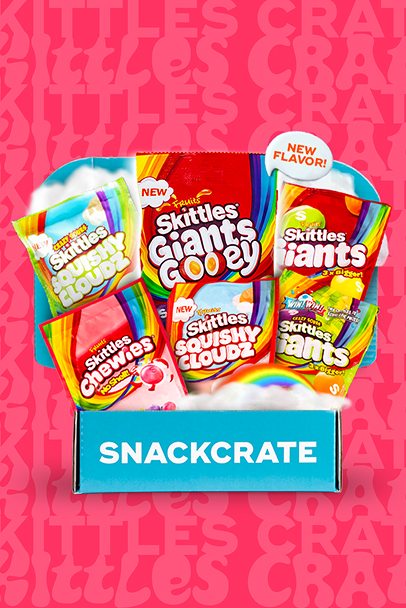Blue SnackCrate box filled with six colorful Skittles candy bags, including Squishy Cloudz, Giants Gooey, Giants, Chewies, and Wildfruit flavors on a pink background.