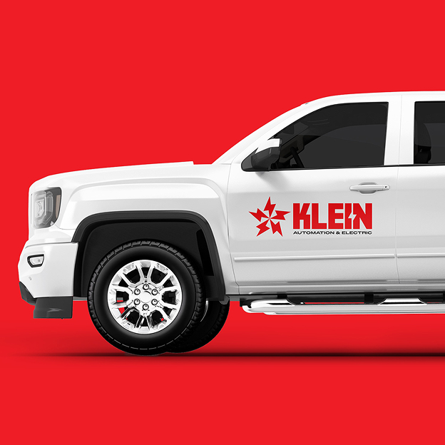 Side view of a white pickup truck with 'KLEIN Automation & Electric' logo in red on the door against a red background.