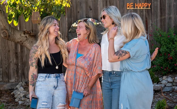 Sherri Banta and 3 friends smiling, talking and embracing.
