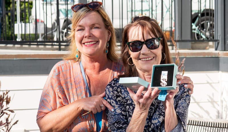 Sherri Banta and a woman holding a Sherri Banta Group branded medallion and smiling.