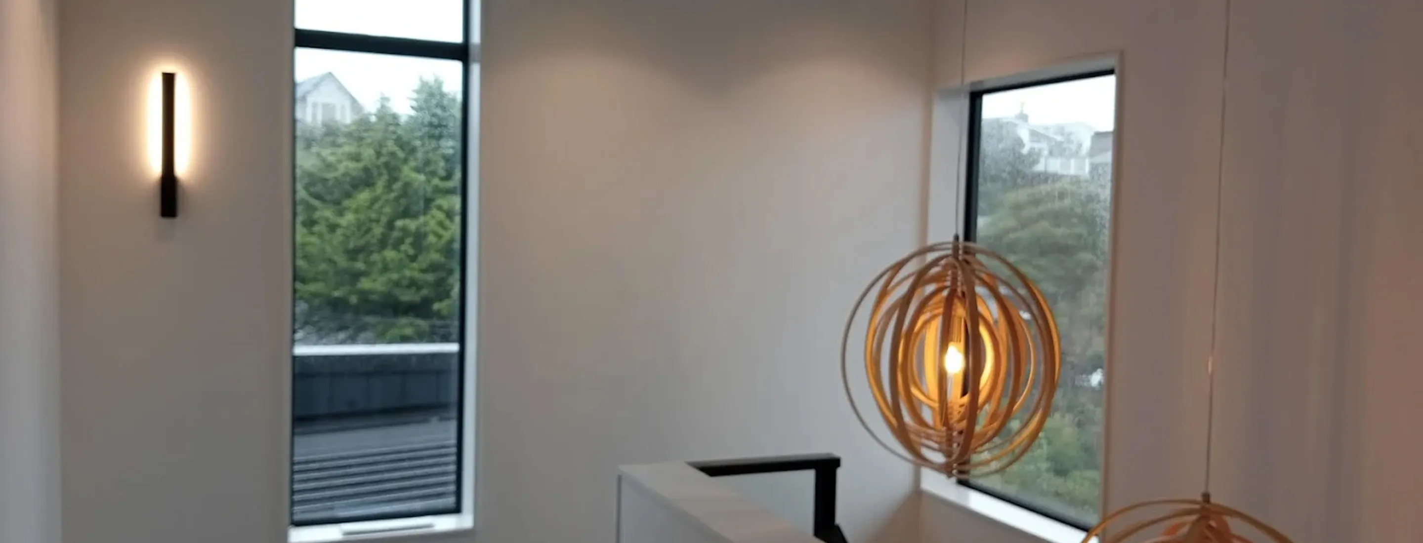Spherical wooden pendant light fixture with Edison bulb against white walls