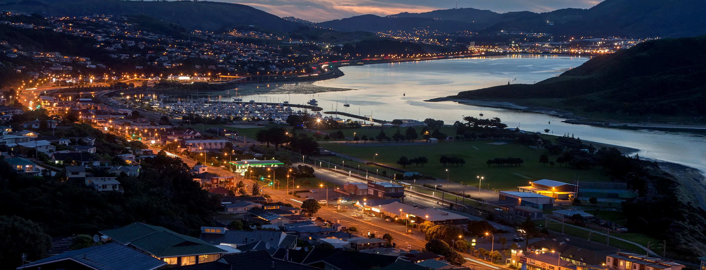 Porirua harbour at dusk with city lights reflecting on water and marina