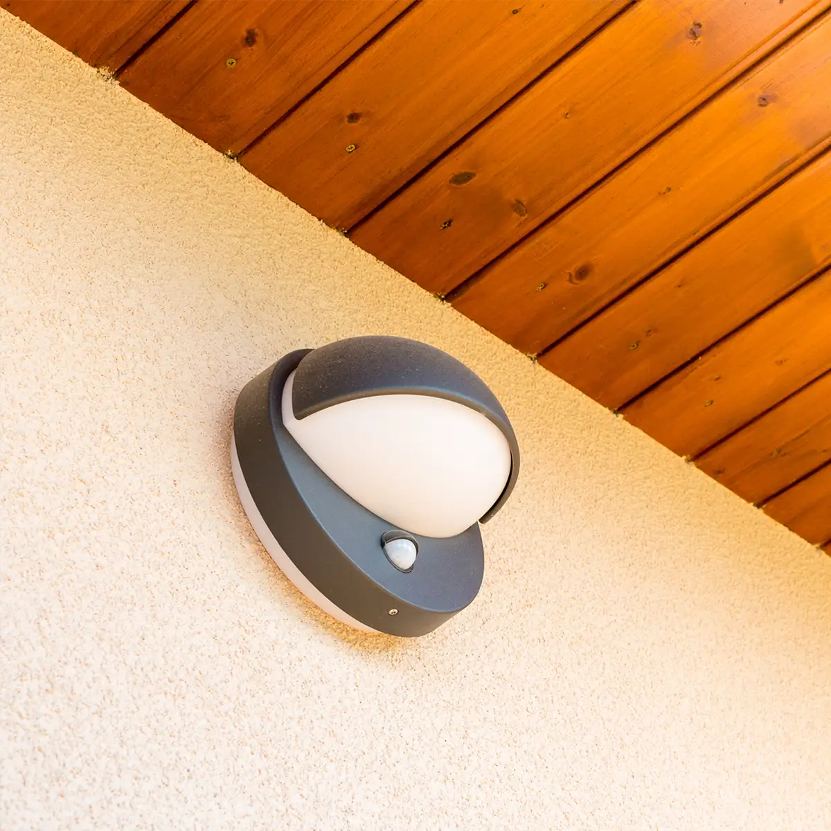 Motion sensor security light mounted on exterior wall under wooden eaves