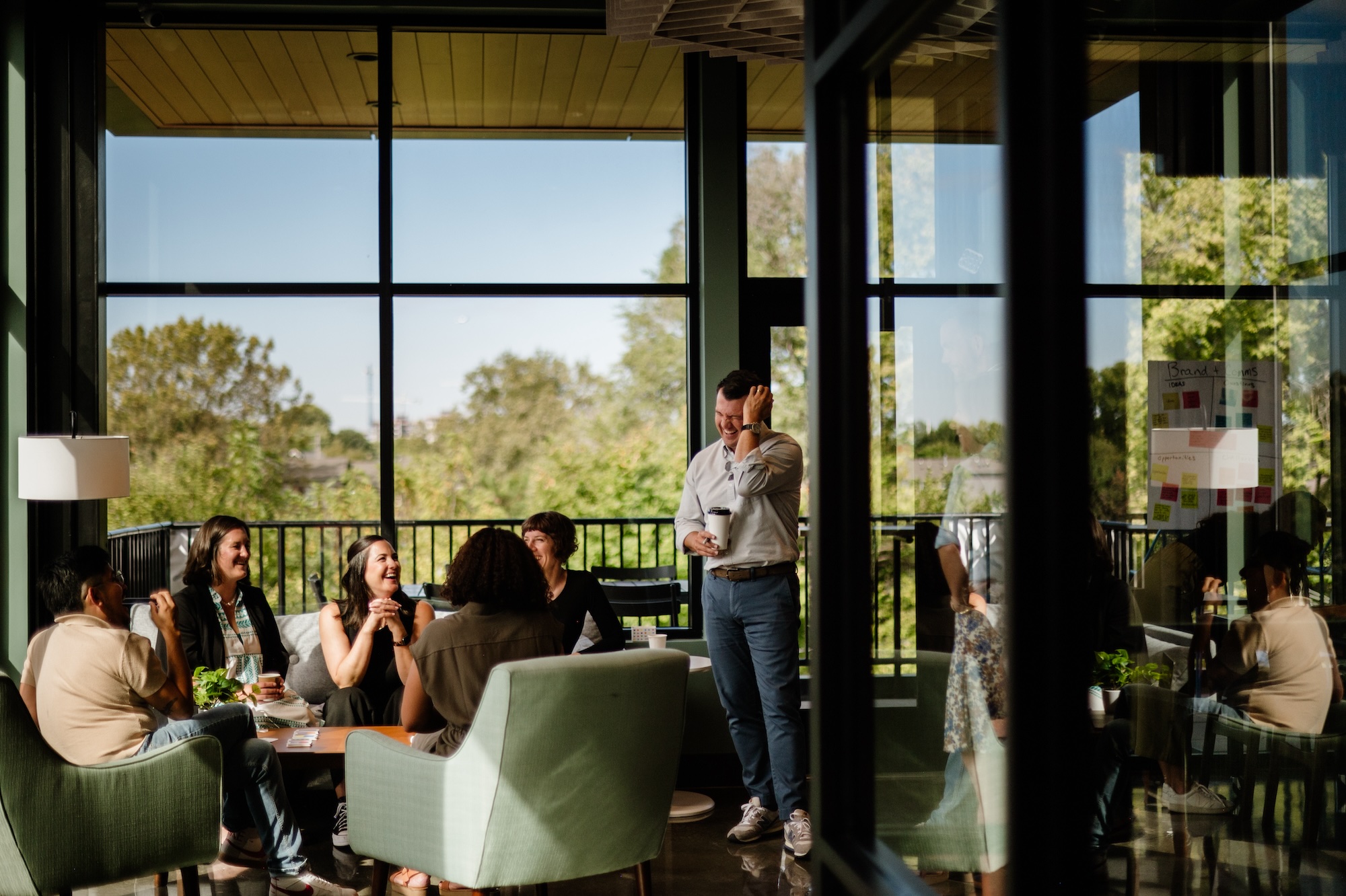 Staff from social impact consultant Friday sit around a coffee table talking and similing.
