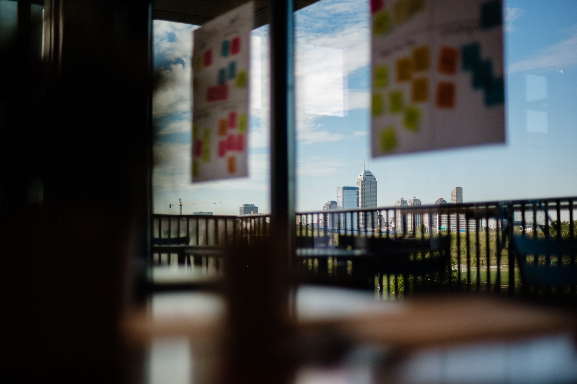The view from inside a workshop by social impact consultant Friday. Inside are posters with brainstorm notes capturing brand, communication and growth ideas. Outside the window is a city skyline.