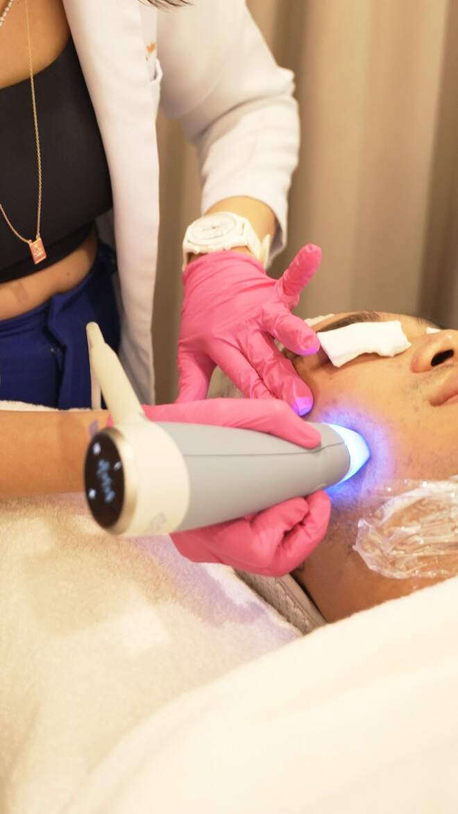 Exion Revive applicator with blue light applied to a client's face