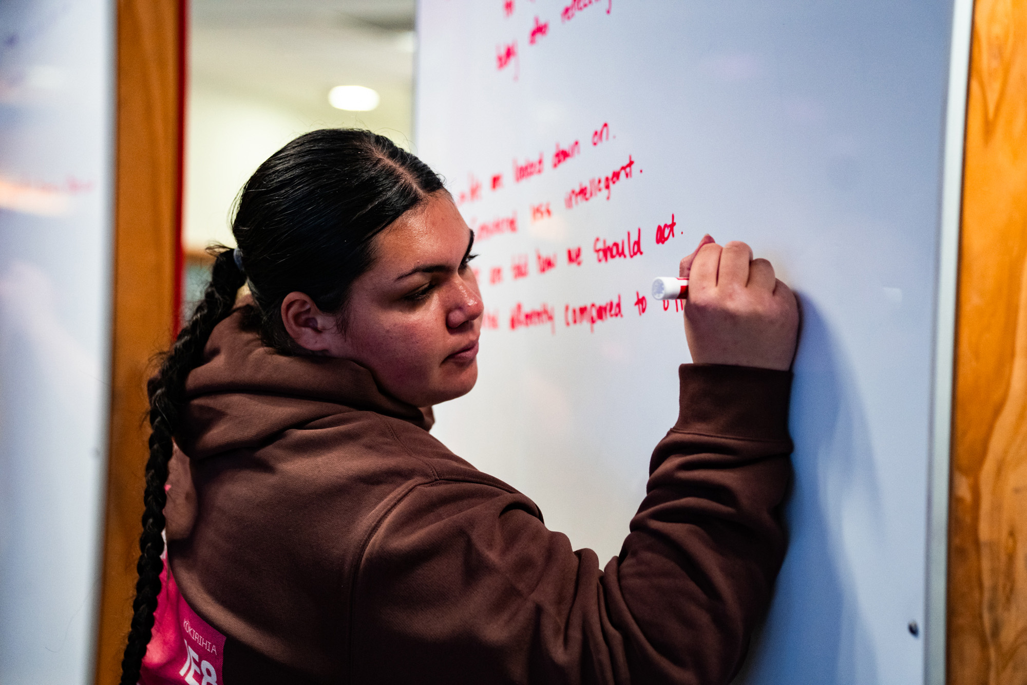 Young woman writes on whiteboard at a Kōkirihia workshop.
