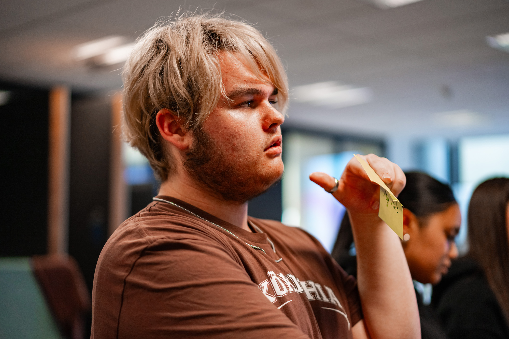 Young man holds a post-it note at a Kōkirihia workshop.
