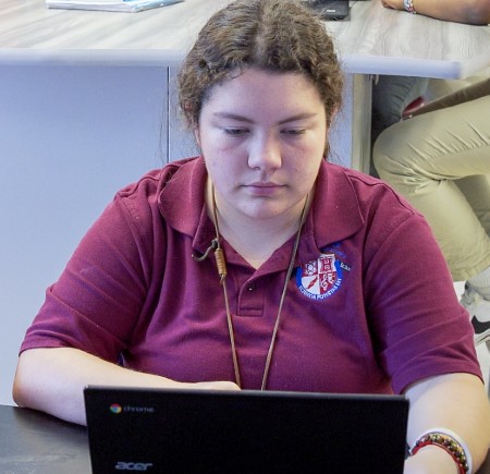 Young woman focused on working with an Acer Chromebook laptop at a desk.