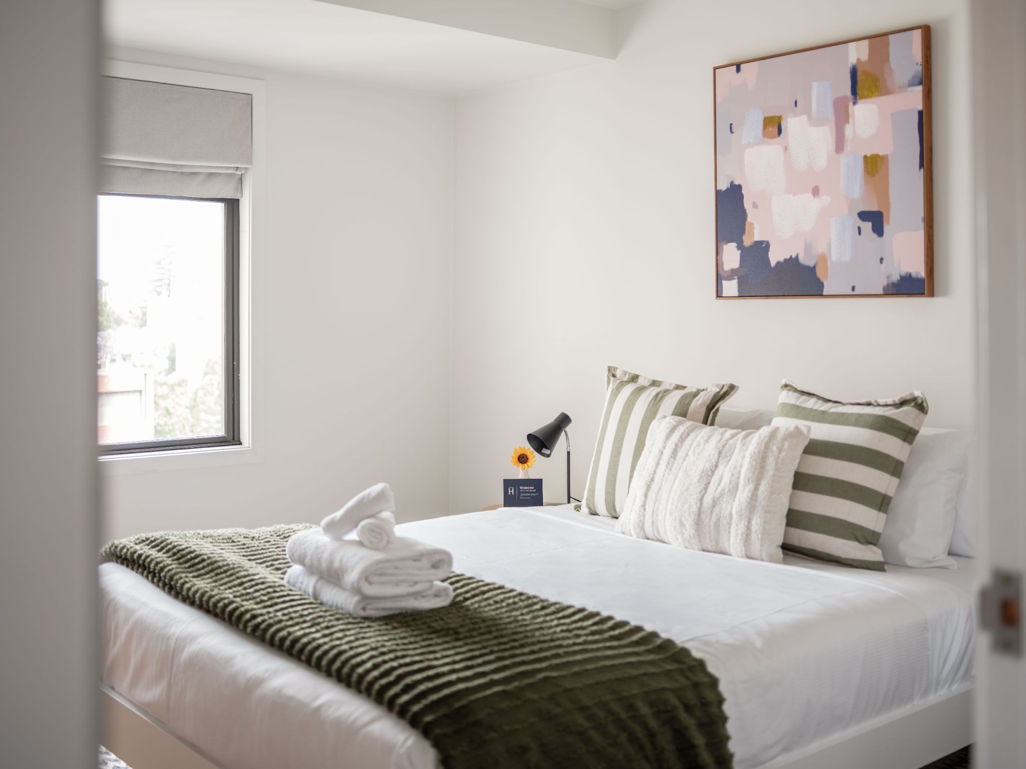 Hotel-quality linen and towels provided by Homello, styled with the owner's decorative cushions and throw.