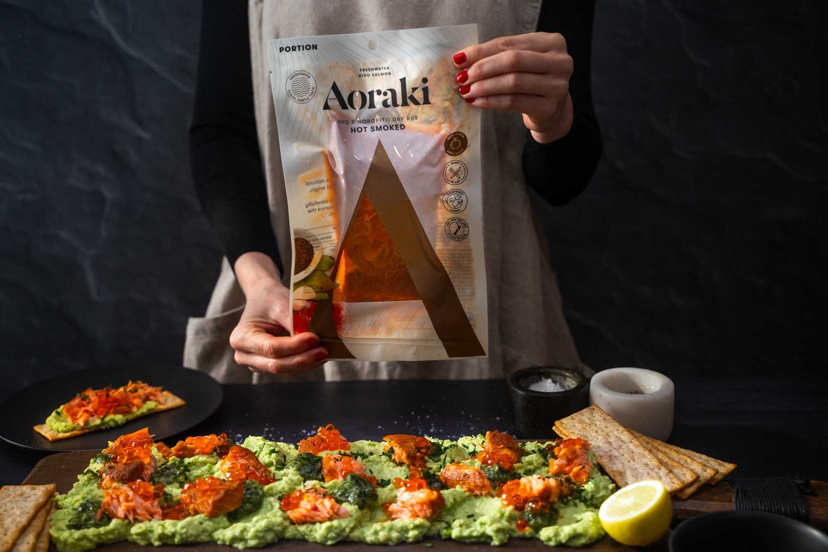 Aoraki BBQ & Horopito Hot Smoked Salmon arranged on a board with creamy avocado and fresh garnishes.