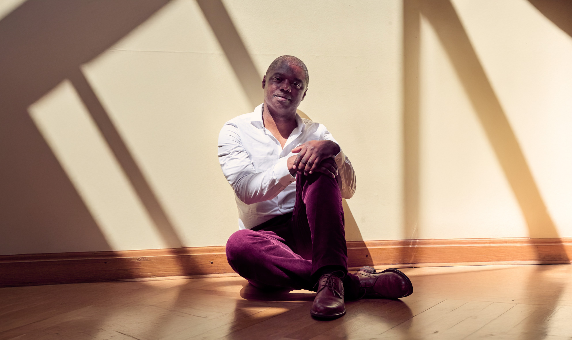 José Londji sitzt entspannt vor einer Wand