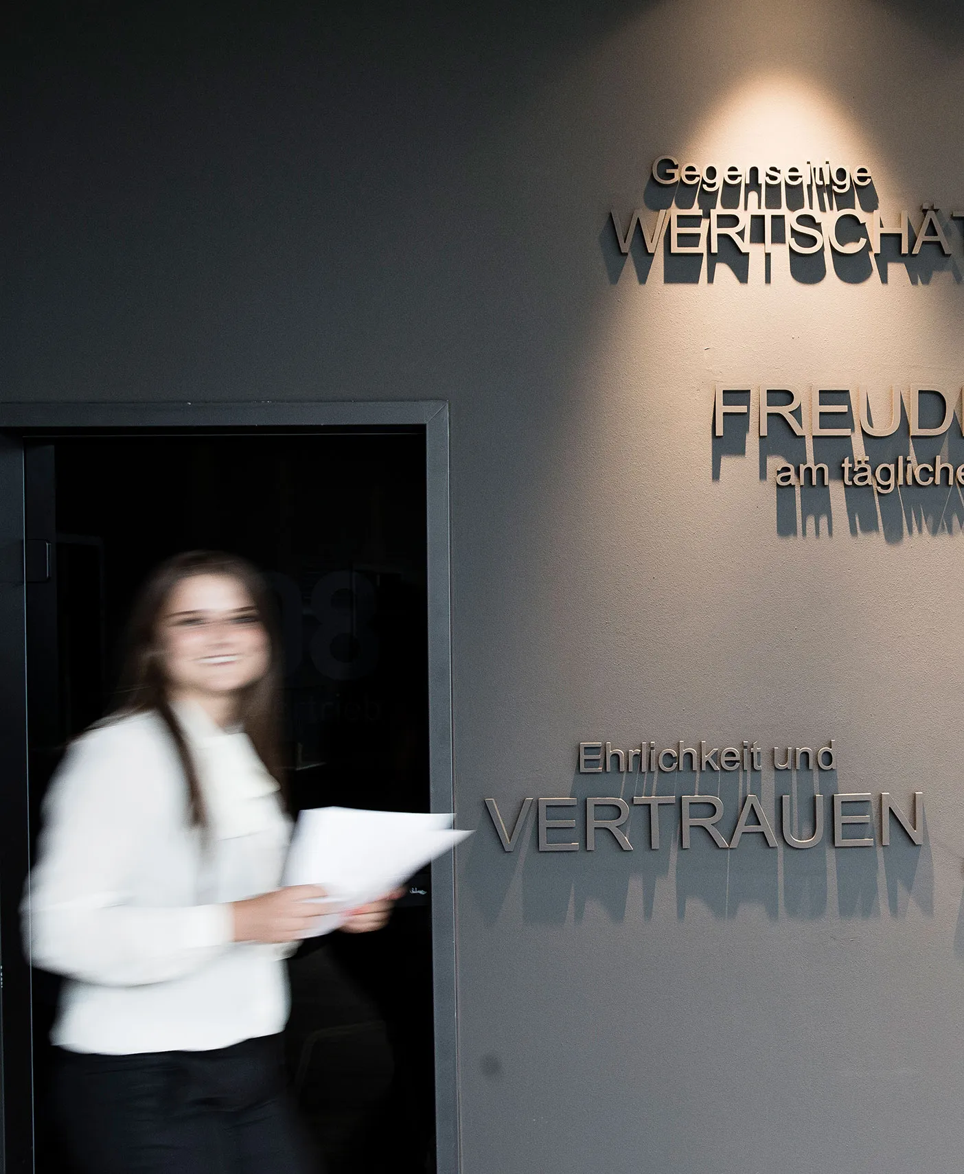 Frau laueft an einer Wand mit Werten vorbei