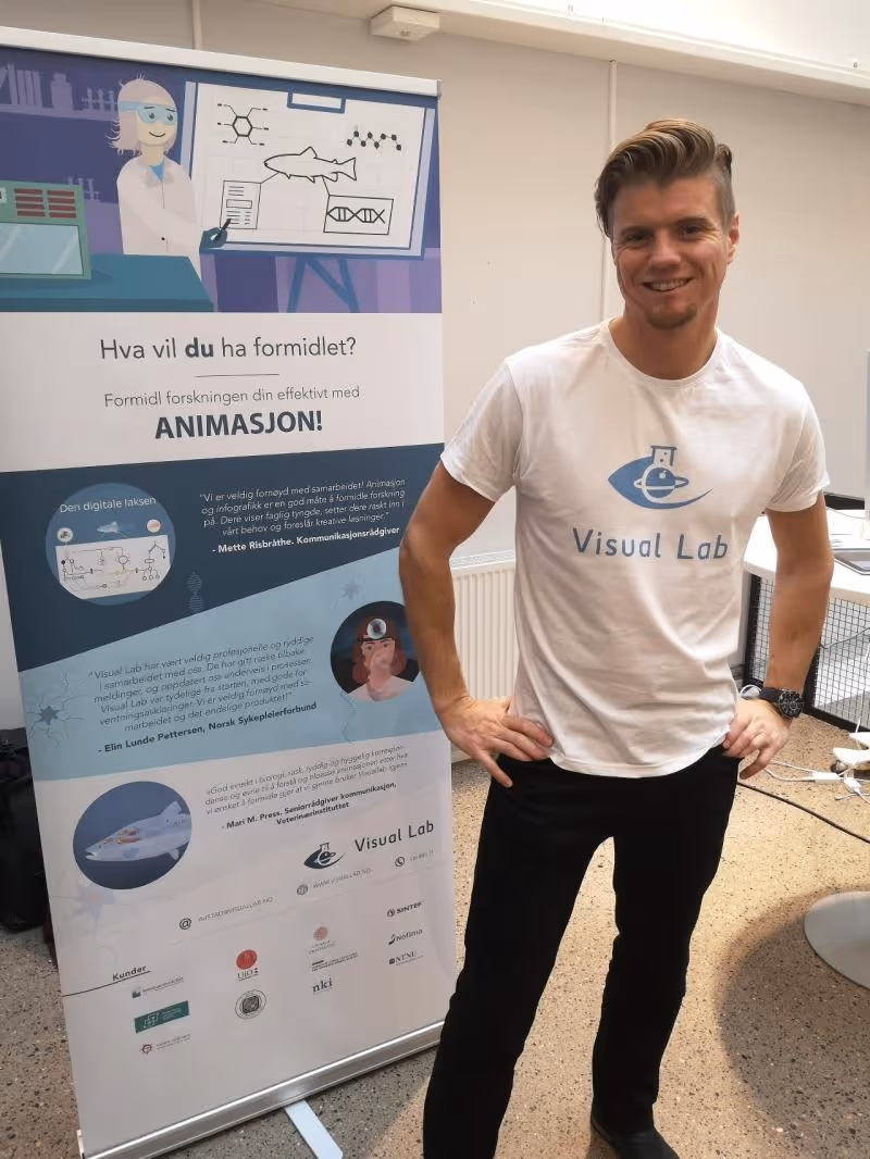 Daglig leder av Visual Lab, Tor Martin Austad, foran roll-up plakat om visuell forskningsformidling.
