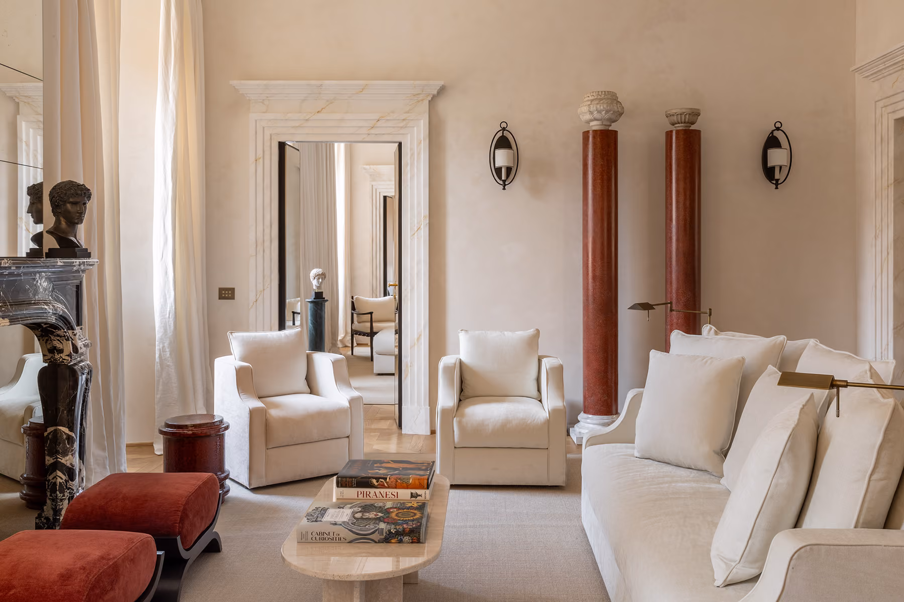 Janus apartment living room with red porphyry columns, a white sofa and armchairs
