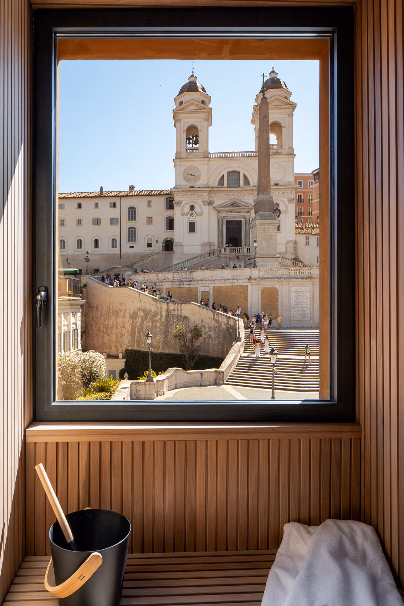 Otium spa sauna window framing the Trinità dei Monti church, with a wooden bucket and ladle