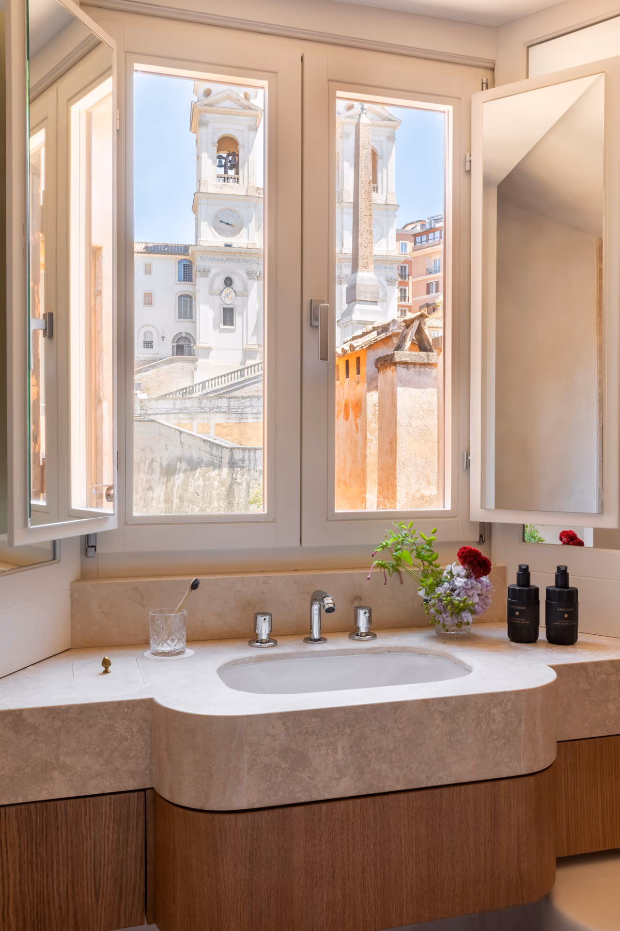 Vesta apartment bathroom with a stone vanity, flowers and a window onto the Trinità dei Monti church