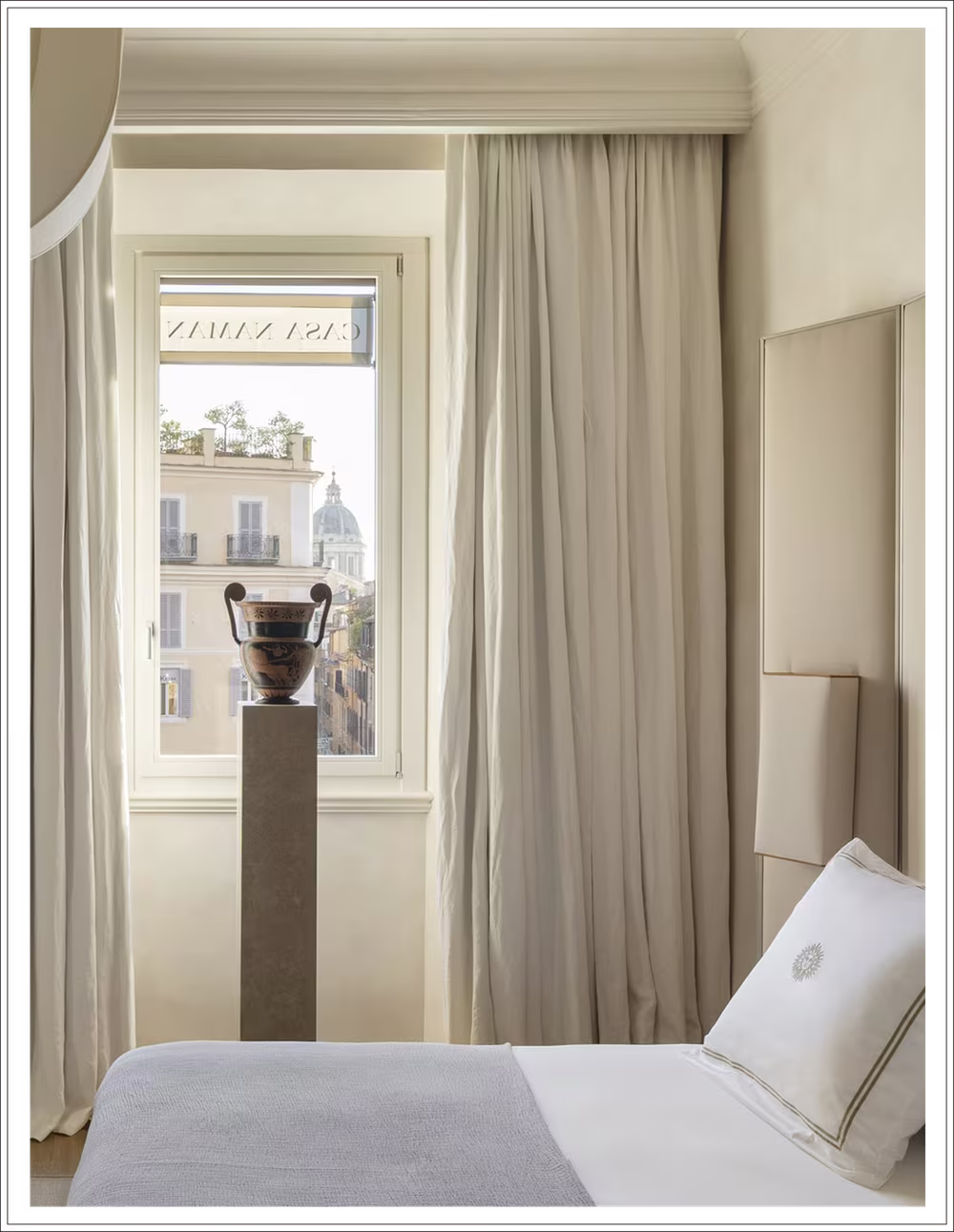 Aeneas apartment bedroom with a curtained window, a stone urn on a plinth and an embroidered pillow