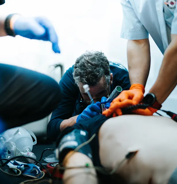 Des professionnels de la santé portant des gants et effectuant une réanimation d'urgence sur un patient.