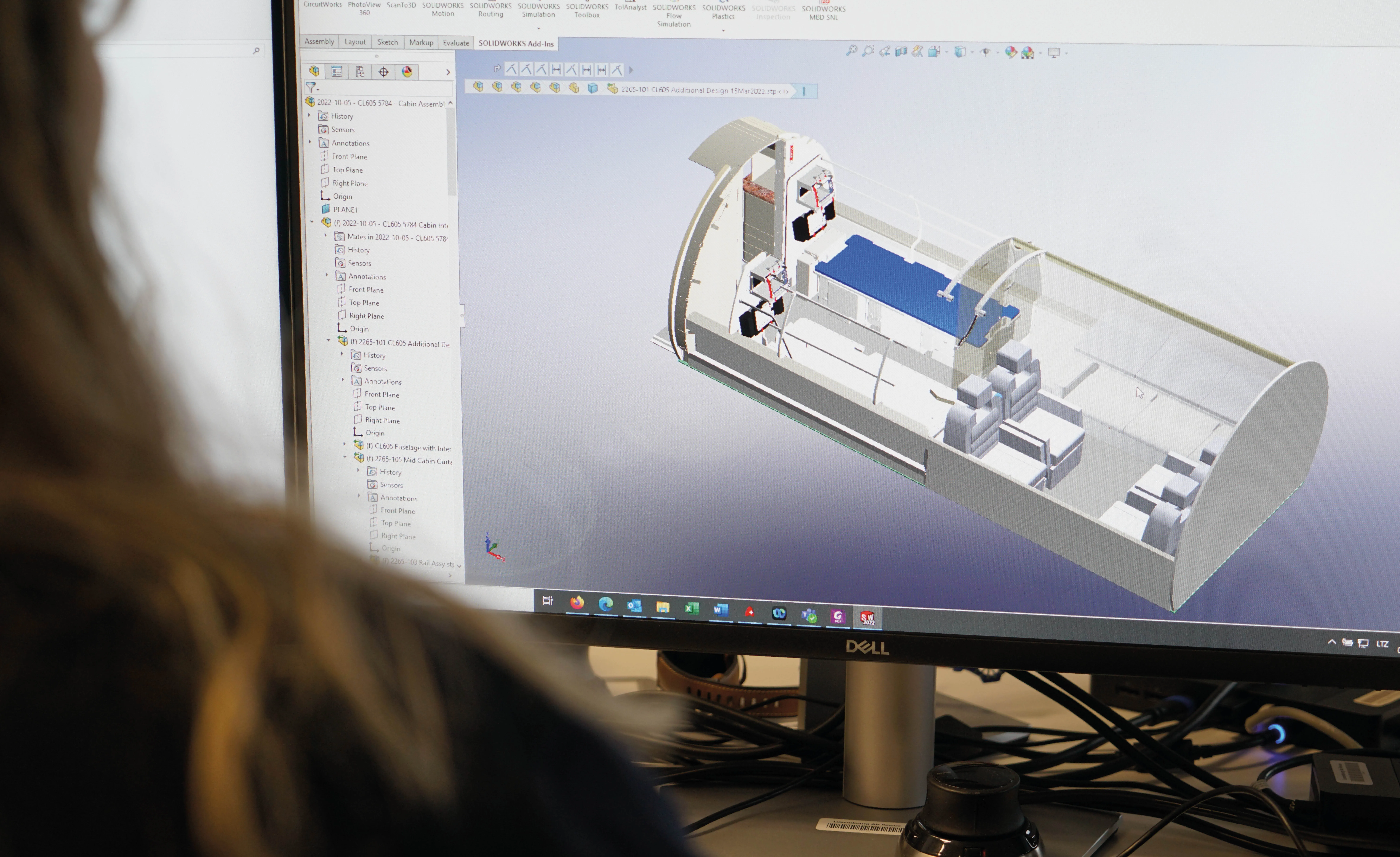 Personne visualisant la conception intérieure de la cabine d'un avion en 3D sur un écran d'ordinateur Dell dans un logiciel de CAO.