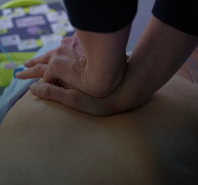 Hands performing chest compressions on a person during CPR training.