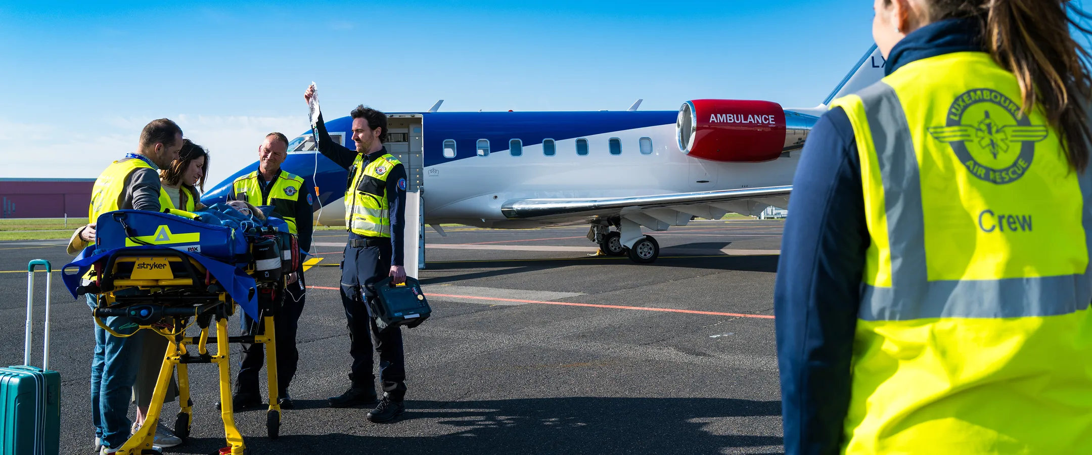 Une équipe de secours médicale s'occupe d'un patient sur une civière à proximité d'un jet d'ambulance sur le tarmac d'un aéroport.