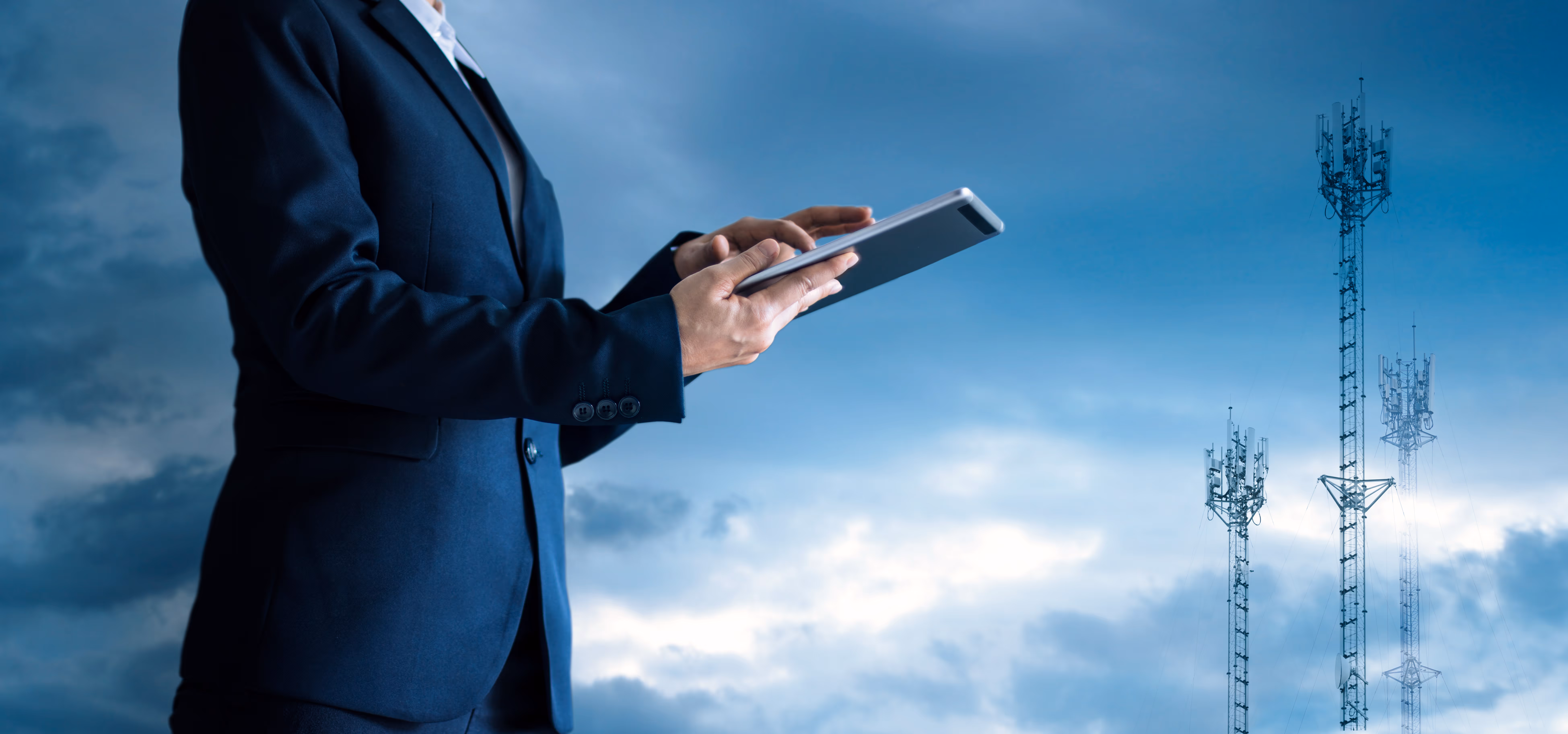 Photo d'une personne sur qui utilise une tablette devant des antennes de réseau
