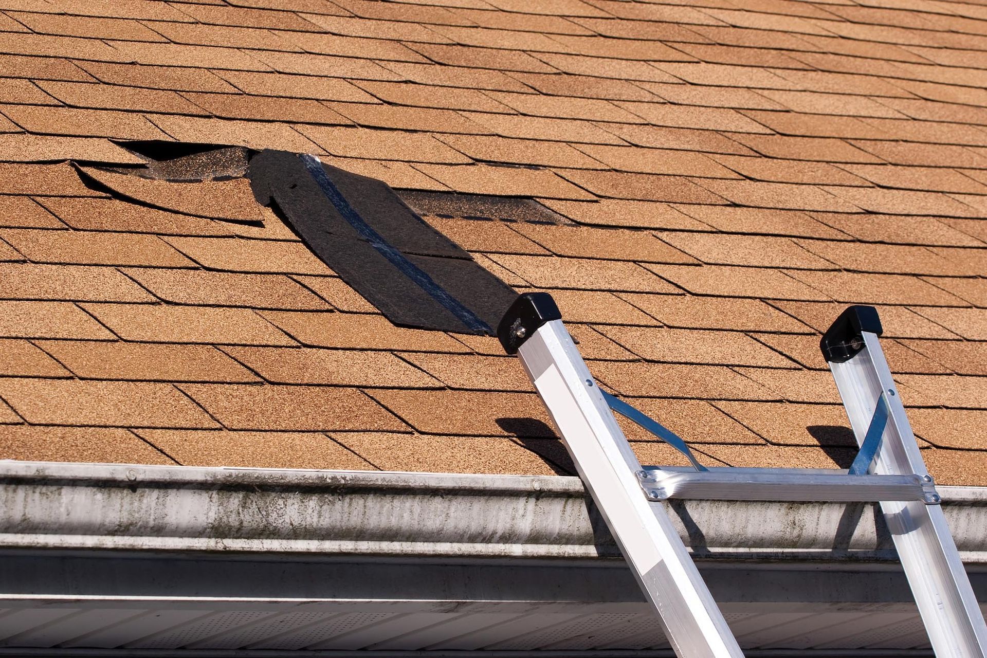 A ladder is sitting next to a roof with a hole in it.