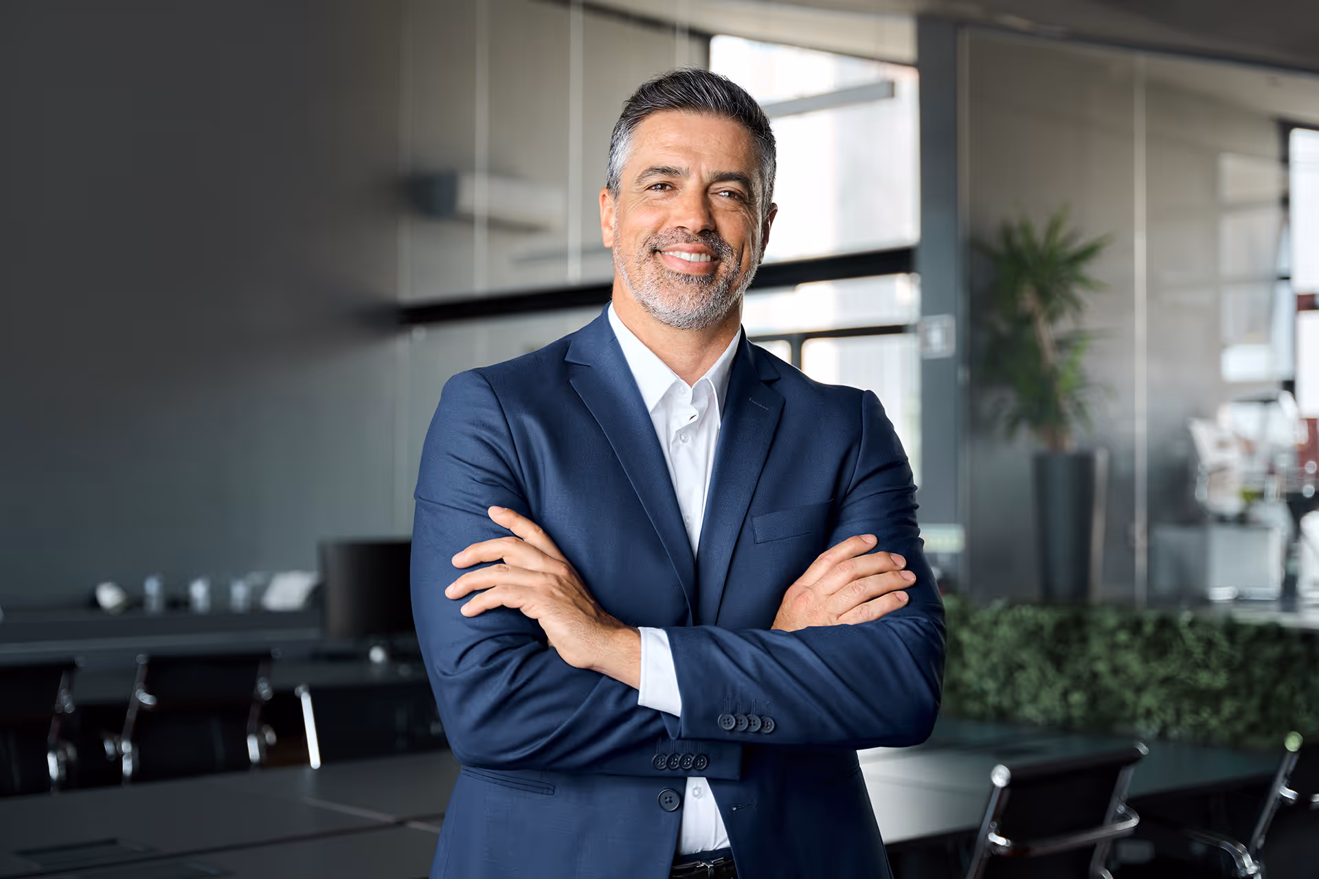 A man with his arms crossed leaning on a meeting rom table