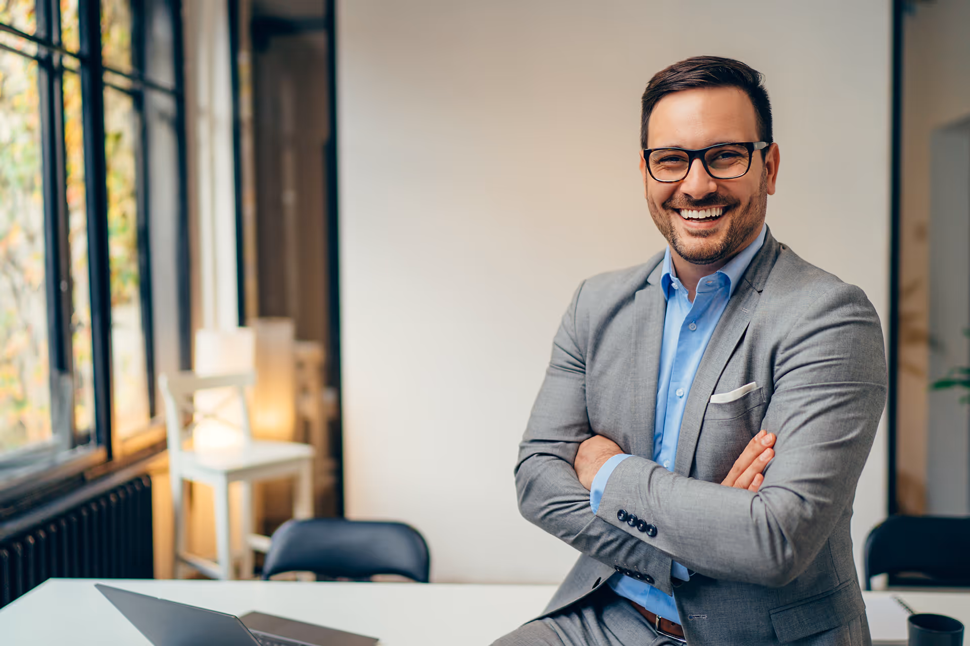 A man smiling whilst leaning on an office desk