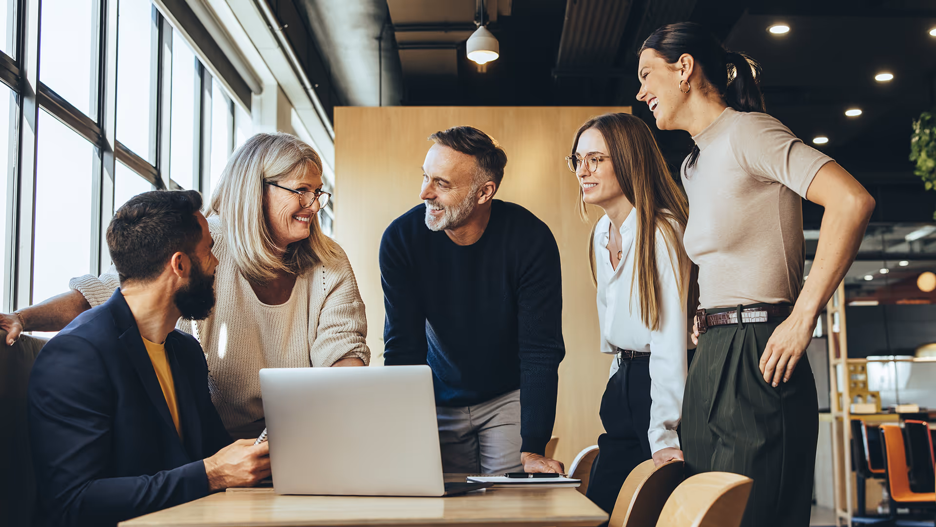 A group of people holding a meeting around a laptop