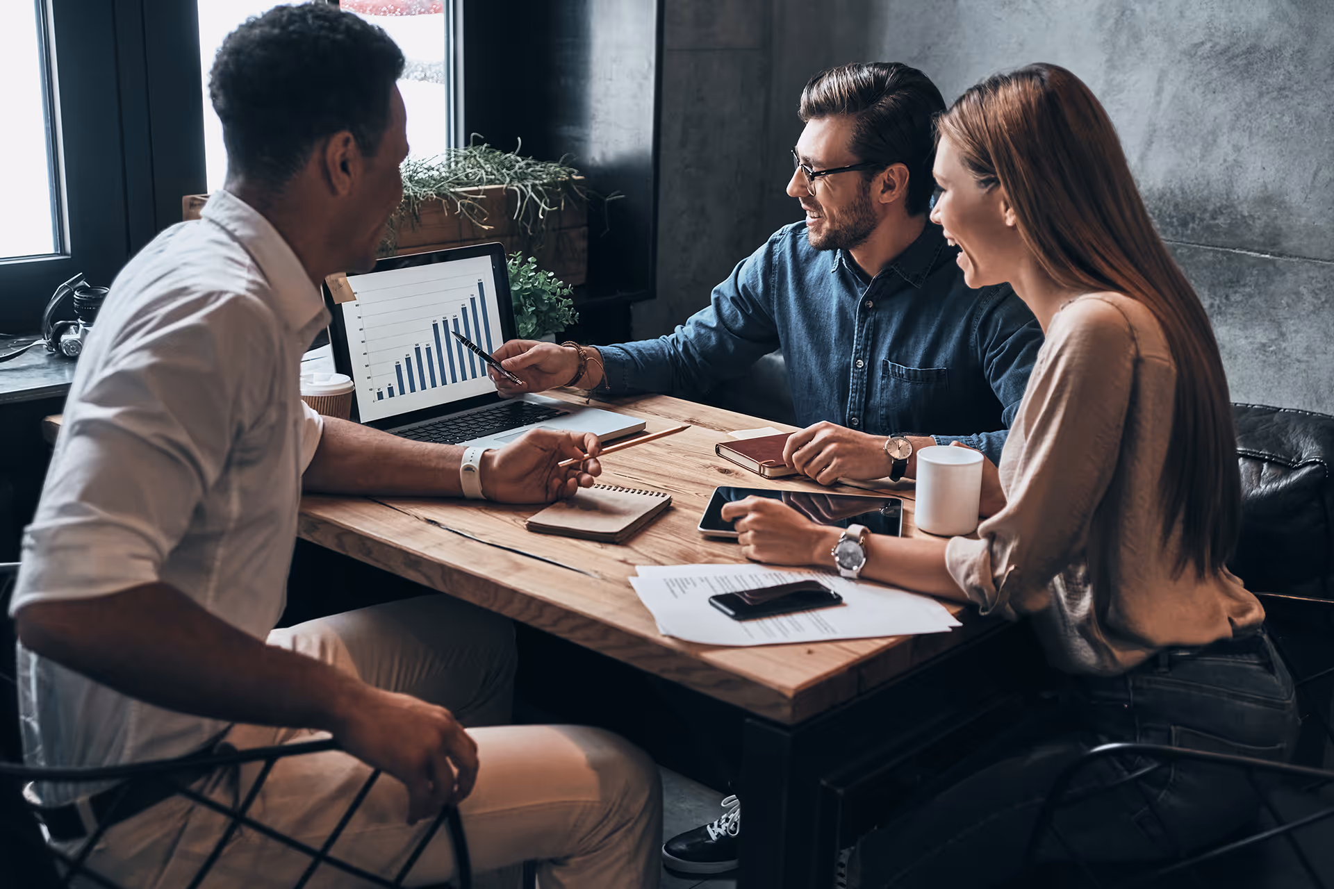 Three people assessing risk and financial charts during a meeting