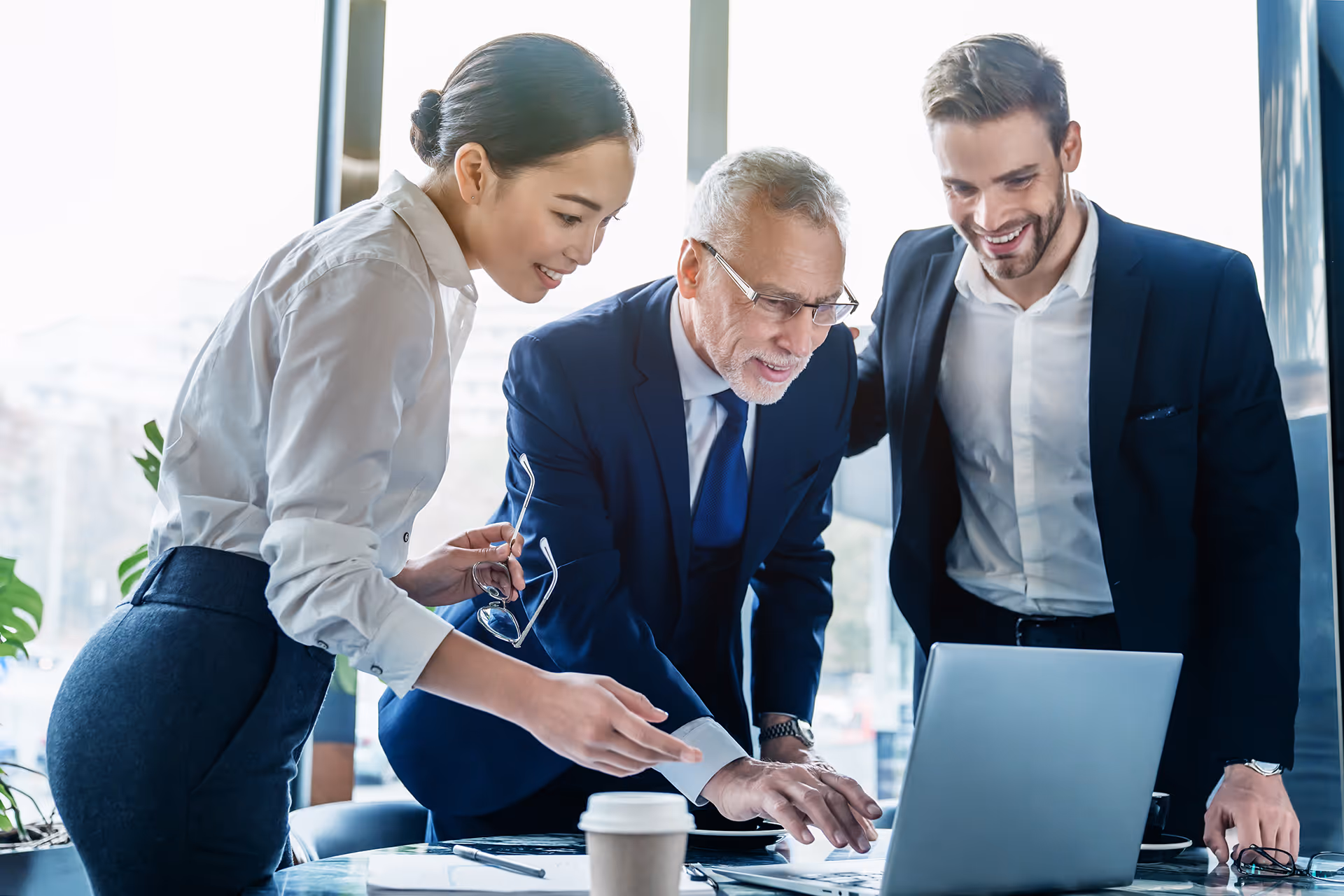 Three people looking at a laptop together in an office — representing insurance solutions for airlines