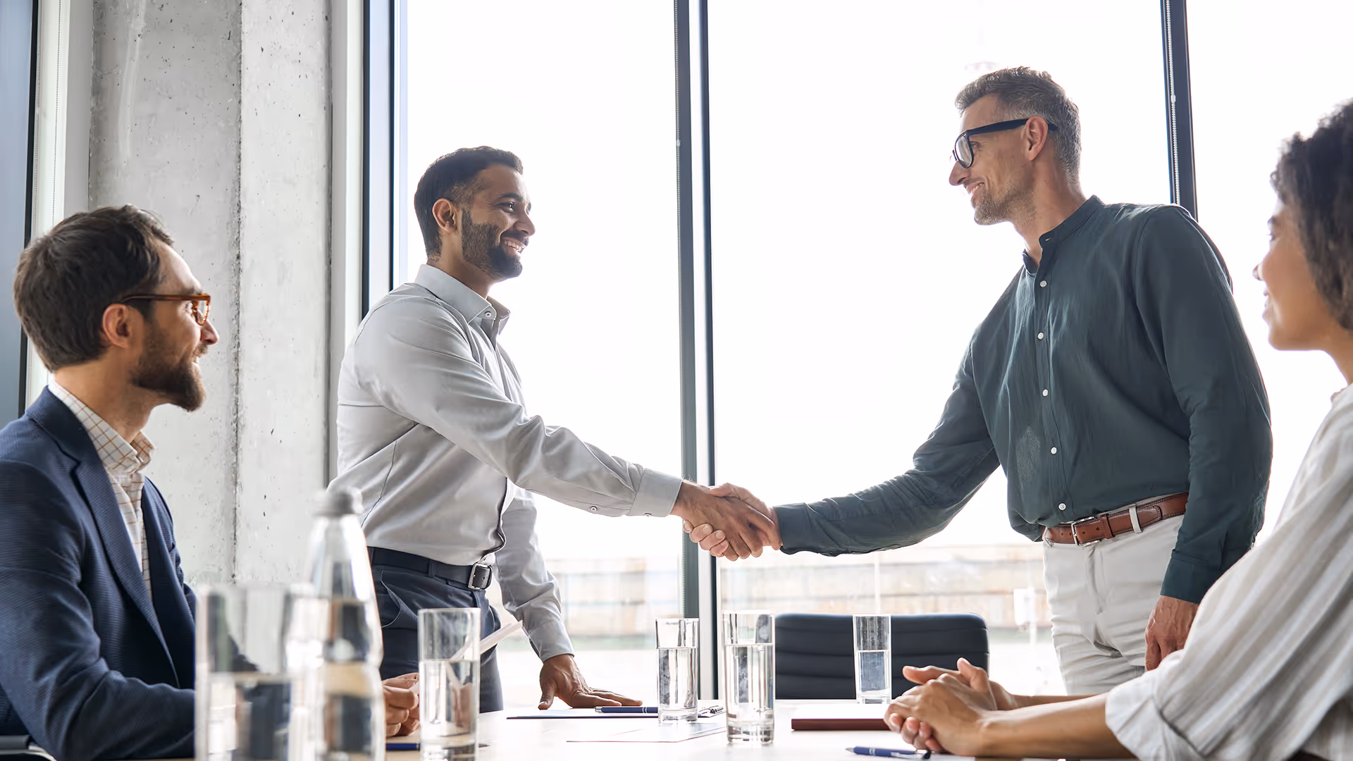 Businessmen shaking hands in a meeting, representing TMU partnerships