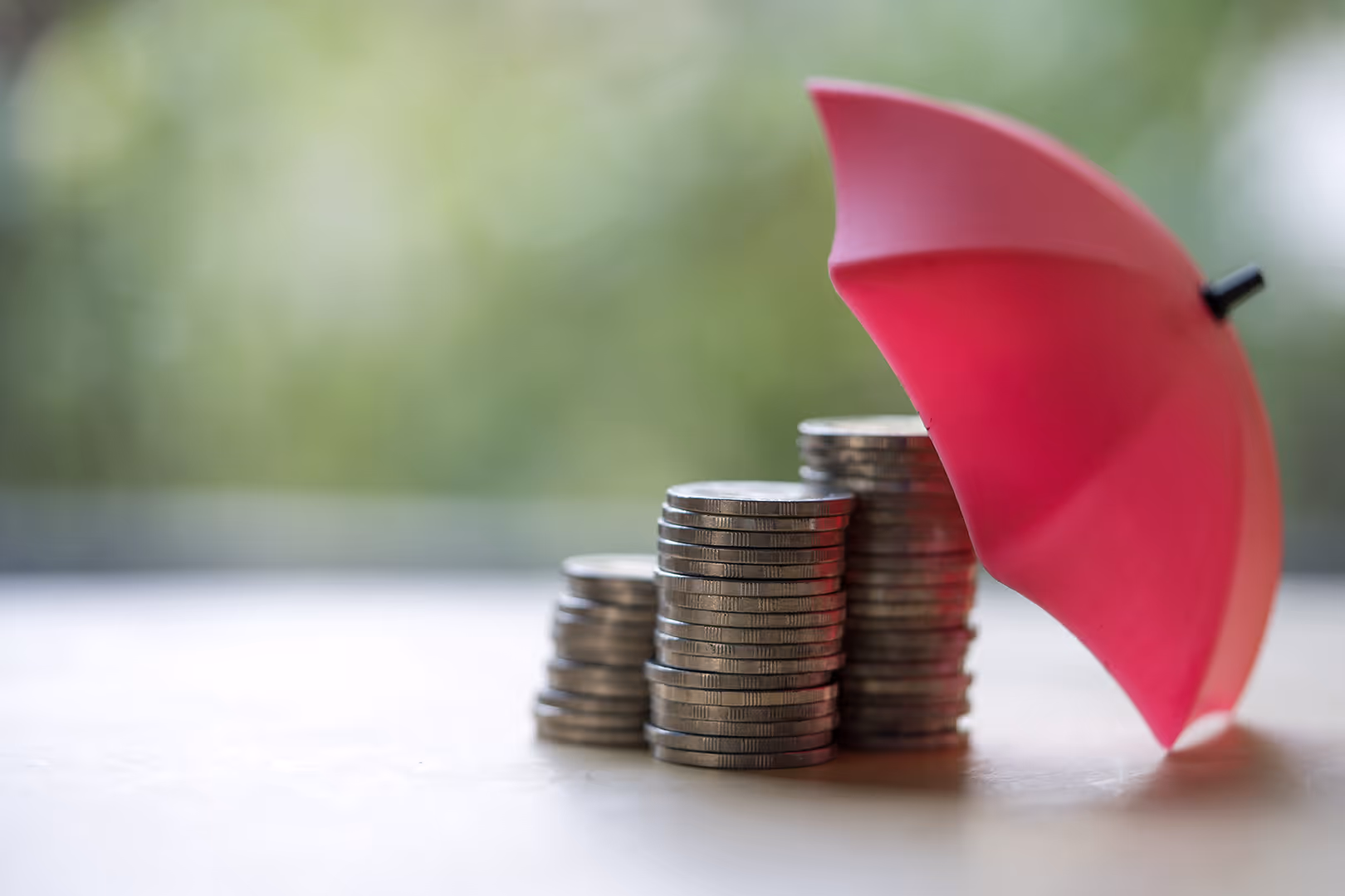 Stacks of coins under a pink umbrella