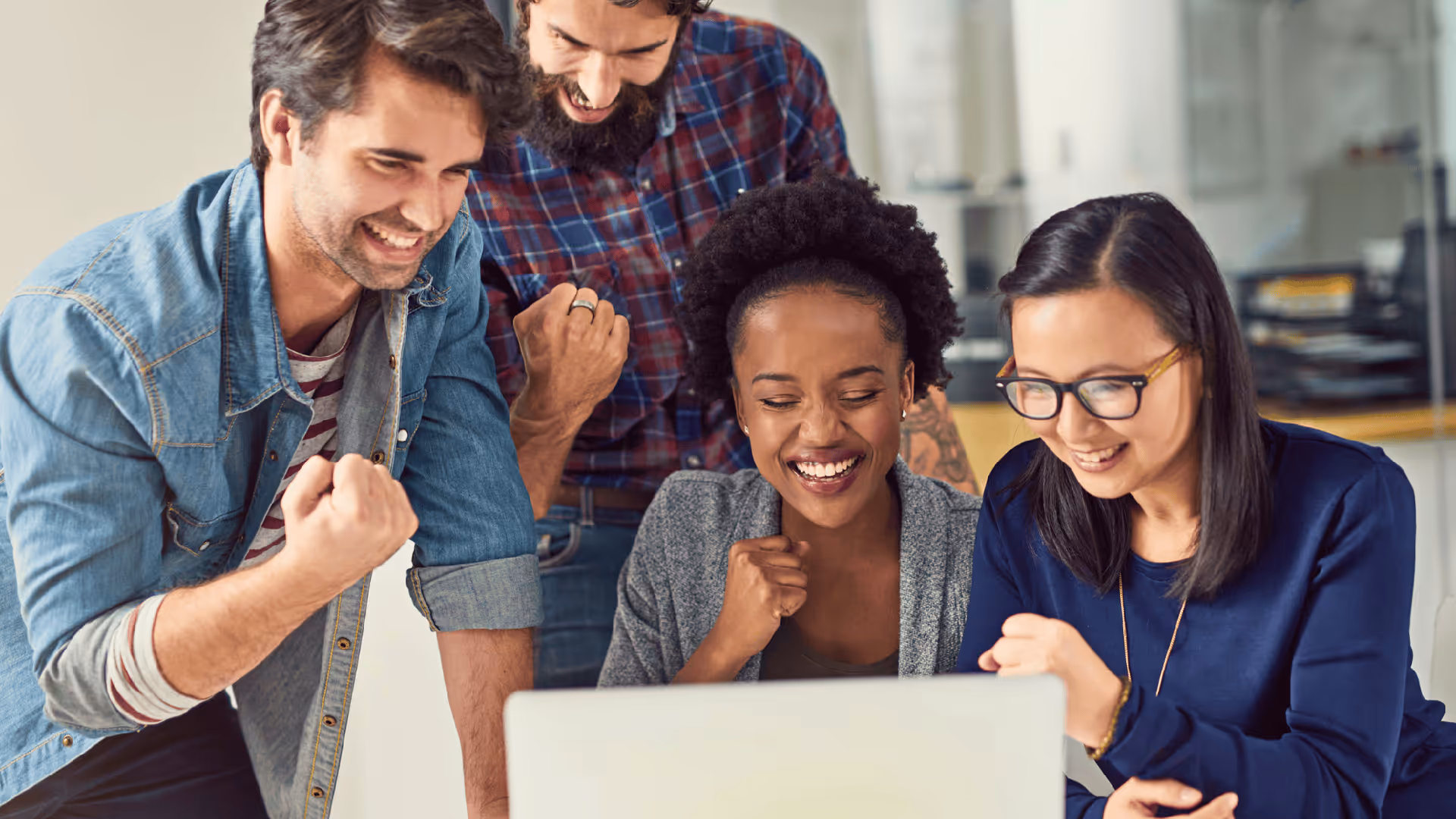 Business team gathered around a laptop celebrating together