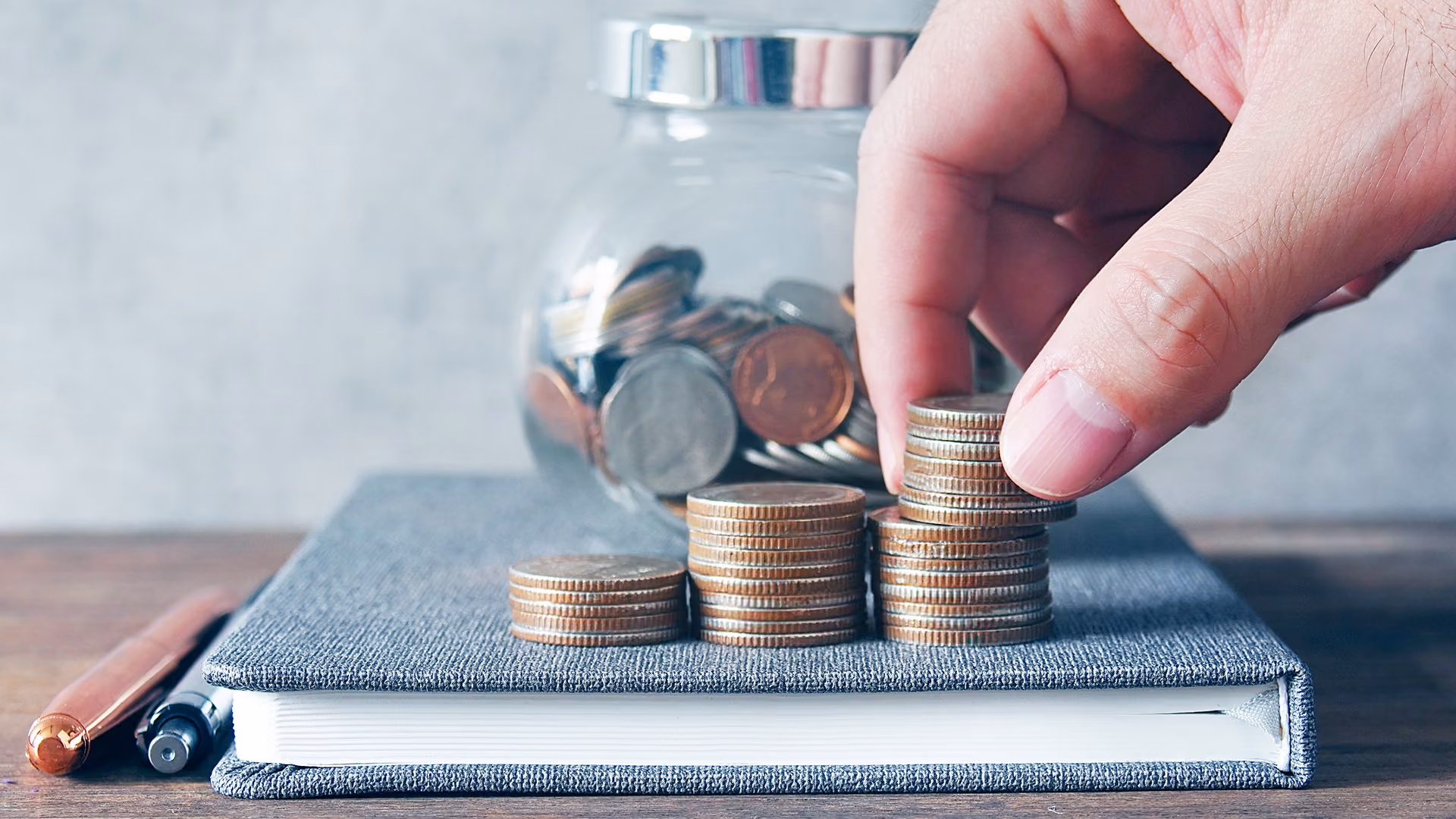 Man stacking coins on a notebook, representing payments risk handbook