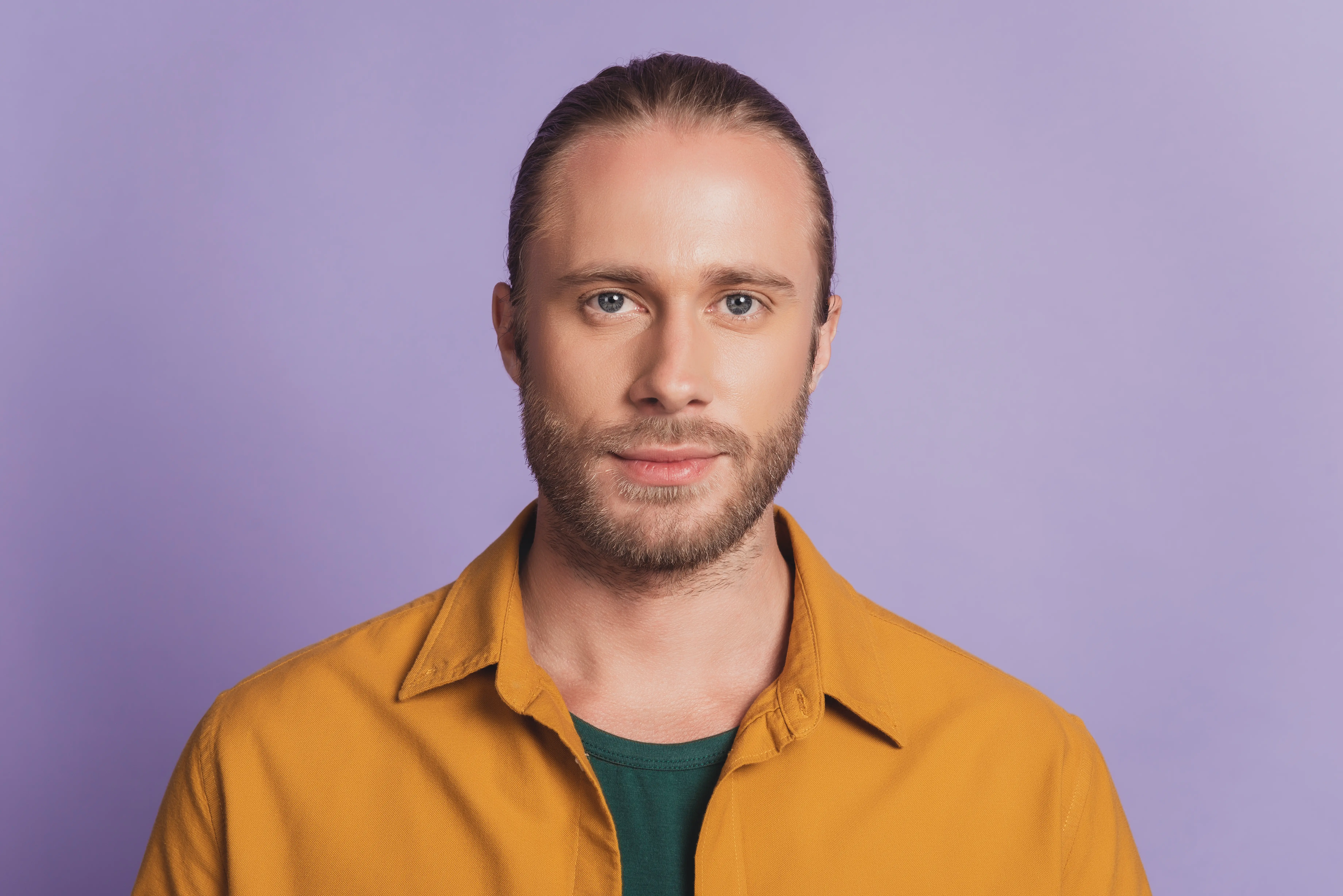 A man wearing a yellow shirt and green undershirt.