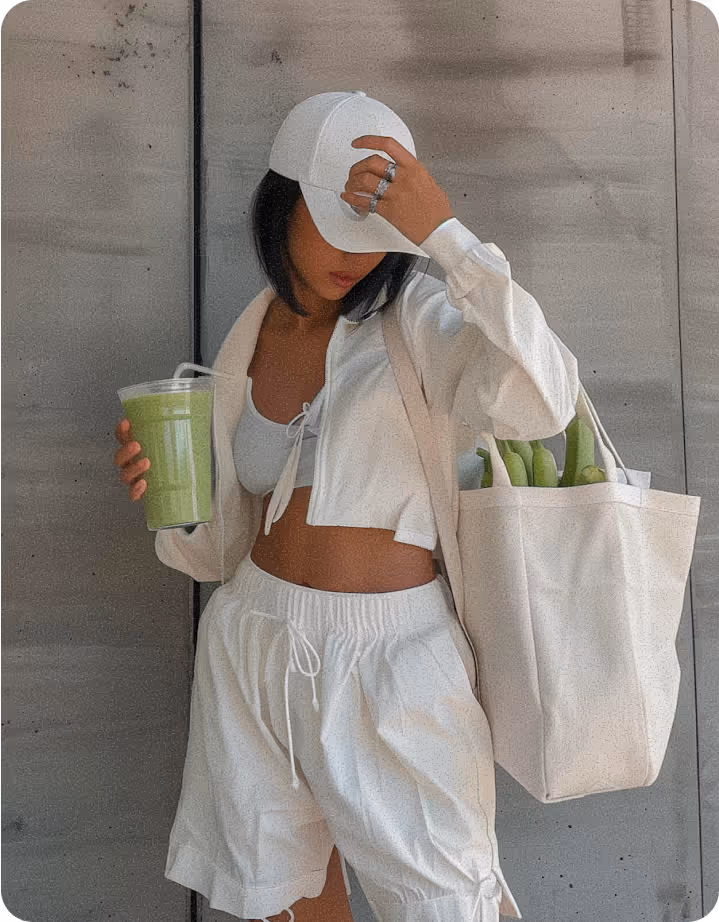 Woman wearing all white sports gear with green smoothie in hand