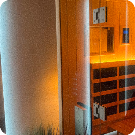 Modern sauna interior with warm orange wood paneling and glass door
